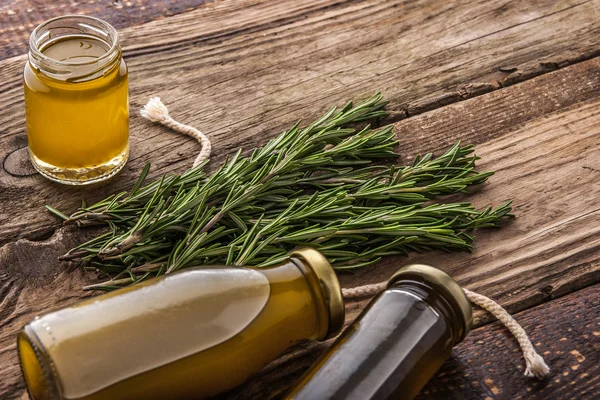 Rosmarin- und Glasgefäße mit Olivenöl auf dem horizontalen Holztisch — Stockfoto