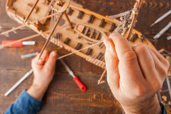 Man collects the vehicle model on the wooden table — Stock Photo, Image