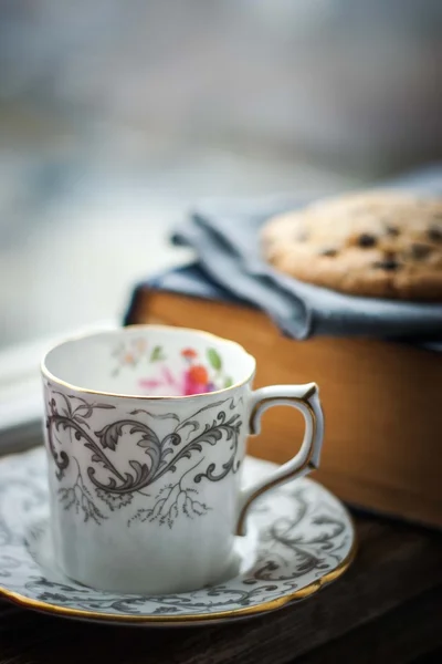 Кавова чашка з розмитим печивом і старою книгою — стокове фото