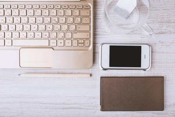 Computer portatile, telefono cellulare, notebook su un tavolo di legno — Foto Stock