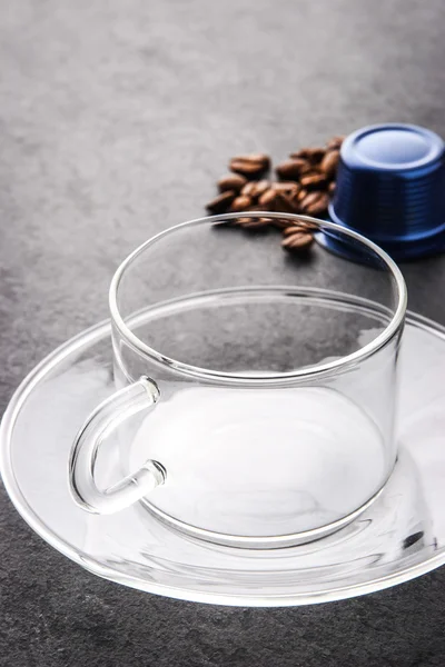 Стеклянная чашка с кофейной капсулой и кофейными зернами вертикально — стоковое фото