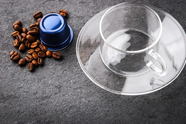 Glass cup with coffee capsule and coffee beans