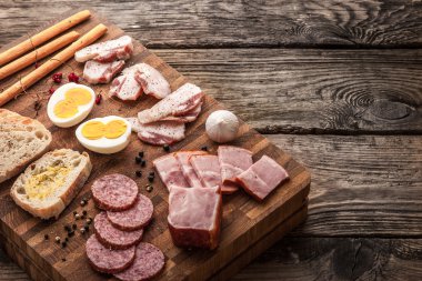 Yumurta, jambon, sosis, ekmek, biber, sarımsak bir kesme tahtası üzerinde 