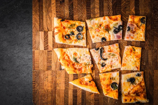 Rebanadas de pizza en una tabla de madera — Foto de Stock