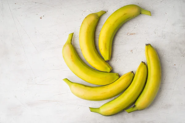Жовті банани покладені вентилятором на білий стіл — стокове фото