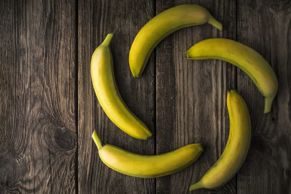Green bananas on an old wooden table — Stock Photo, Image