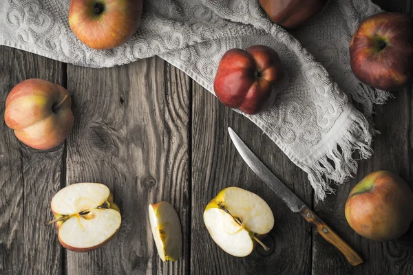 Röda äpplen och apple halvor på ett träbord — Stockfoto