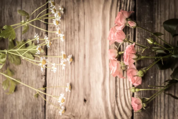 Rosas e margaridas em uma mesa de madeira — Fotografia de Stock