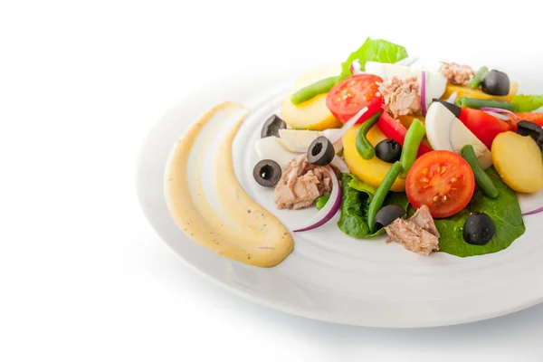 Салат Nicoise на белой тарелке с горизонтальным соусом — стоковое фото