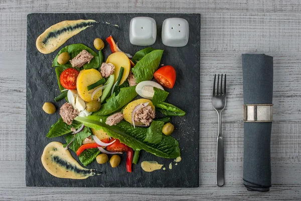 Ensalada de Nicoise en la piedra negra con servilleta y tenedor —  Fotos de Stock