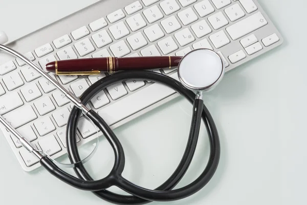 Estetoscópio, caneta-tinteiro e teclado na mesa do médico — Fotografia de Stock