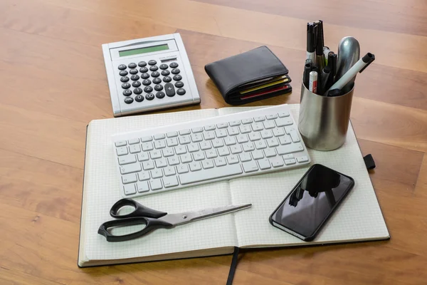 Drewniane biurko z klawiatury, nożyczki, smartphone i Notebook — Zdjęcie stockowe