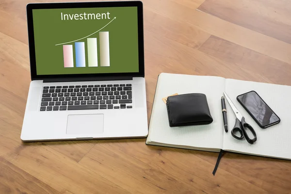 Wooden desk with computer and notebook - chart Investment — Stock Photo, Image