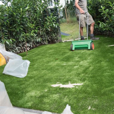 professional gardener puts sand on artificial turf clipart