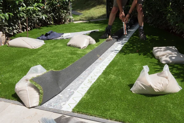 Professional gardener is glueing artificial turf to fit — Stock Photo, Image