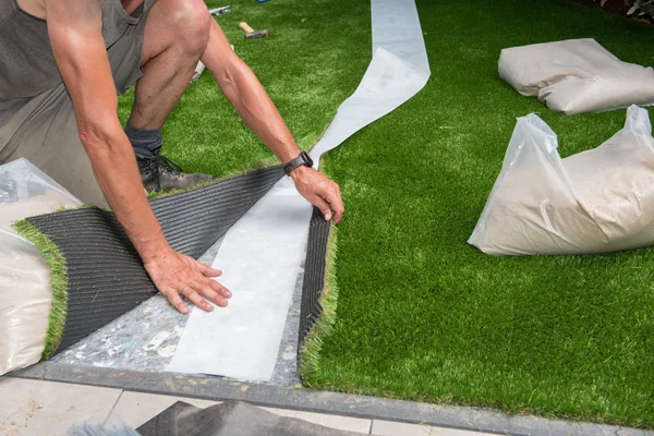 Jardinero profesional está cortando césped artificial para adaptarse —  Fotos de Stock