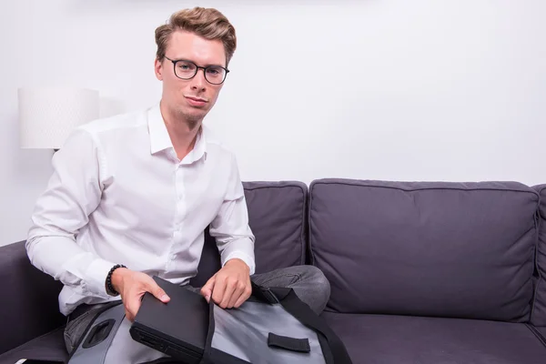 Young business man packing his bag on couch — Stock Photo, Image