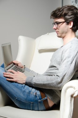 Genç adam bilgisayarla çalışıyor.