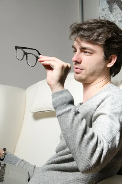 Młody człowiek patrzy na jego okulary — Zdjęcie stockowe