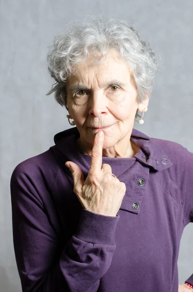 Stará žena s prstem na ústech — Stock fotografie