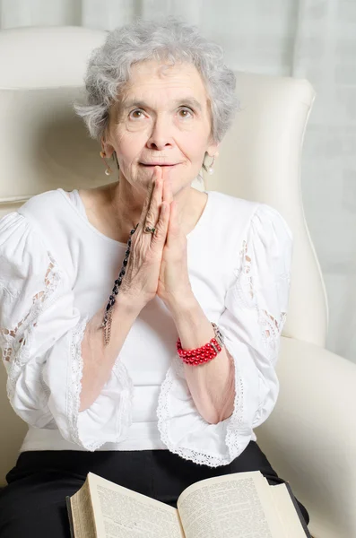 Stará žena s Bibli a modlí se růženec — Stock fotografie