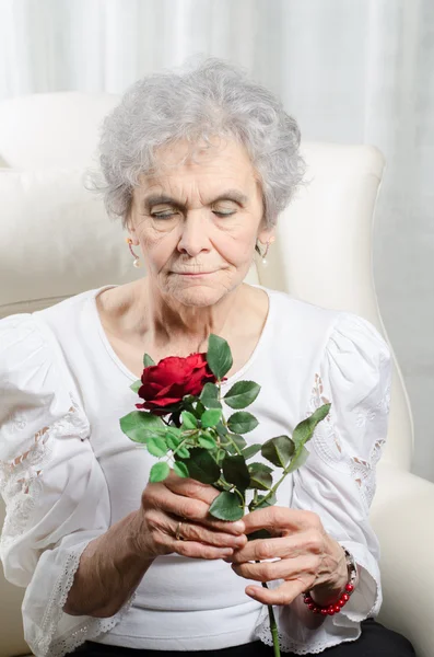 Stara kobieta wygląda na róży — Zdjęcie stockowe