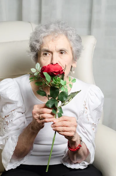 Stará žena voní růže — Stock fotografie