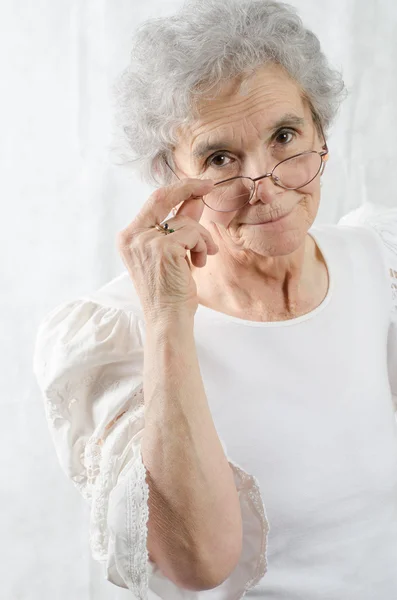 Vecchia donna sta guardando oltre i suoi occhiali — Foto Stock