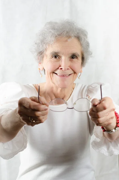 Old woman is offering her glasses — Stock Photo, Image