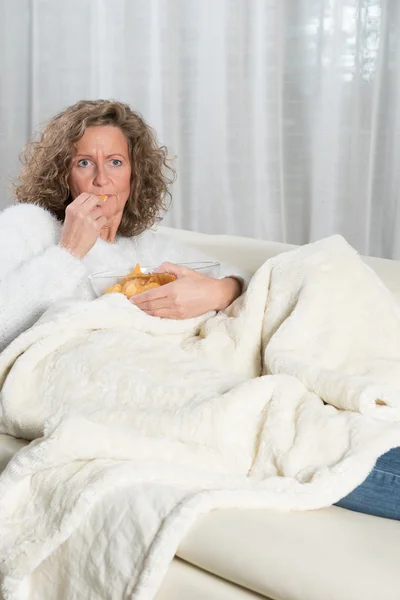 Mujer comiendo patatas fritas y mirando televisión — Foto de Stock