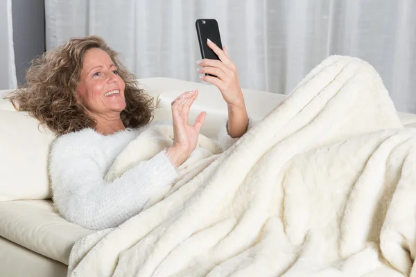 Женщина читает сообщения на смартфоне и смеется — стоковое фото