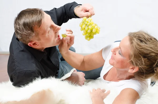 Homem provocando mulher com uvas — Fotografia de Stock