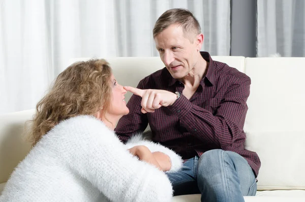 Man och kvinna talar på soffan - har han fingret på hennes näsa — Stockfoto