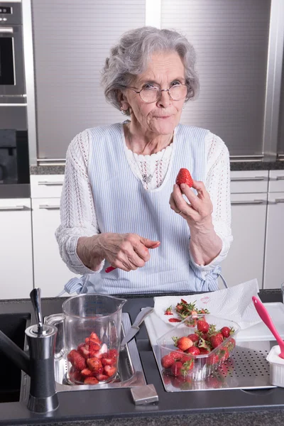 Активная пенсионерка готовит клубнику на кухне — стоковое фото