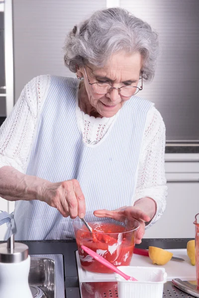 Активная пенсионерка готовит клубнику — стоковое фото