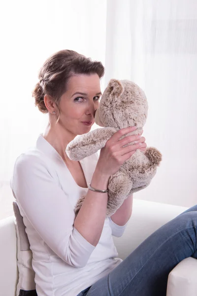 Woman sitting in armchair with teddy — Stock Photo, Image