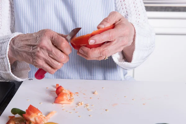 Active senior preparing paprika in kitchen — Stock Photo, Image