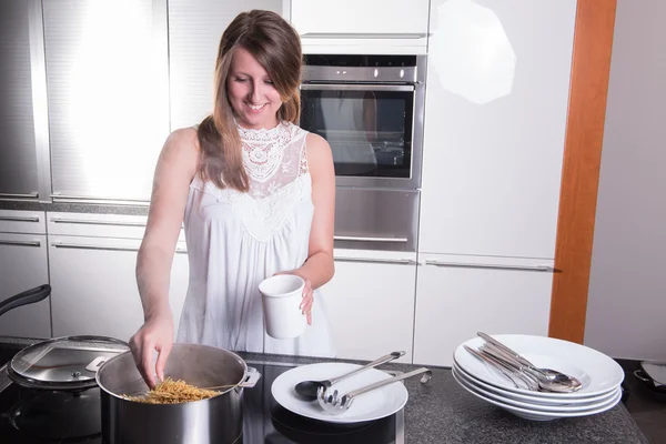 Hermosa chica cocinar espaguetis en la cocina — Foto de Stock