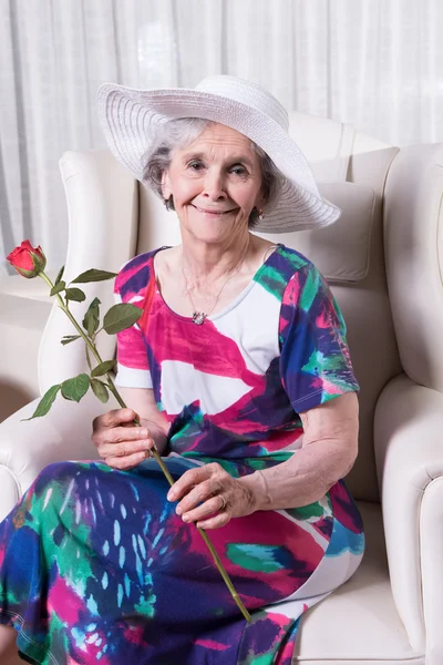Active female senior with rose in her hand — Stock fotografie