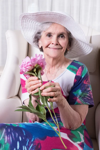 Active female senior smelling a flower — Zdjęcie stockowe