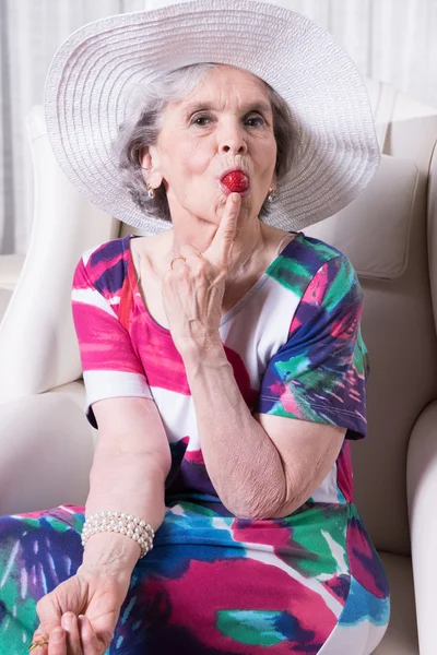 Active female senior eating strawberry — Stock fotografie