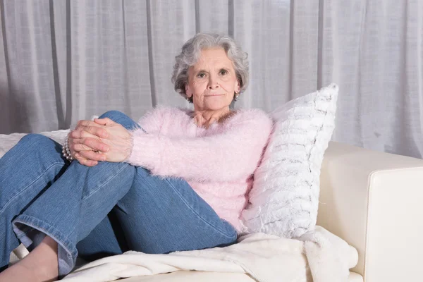 Active female senior relaxing on couch istening — Zdjęcie stockowe