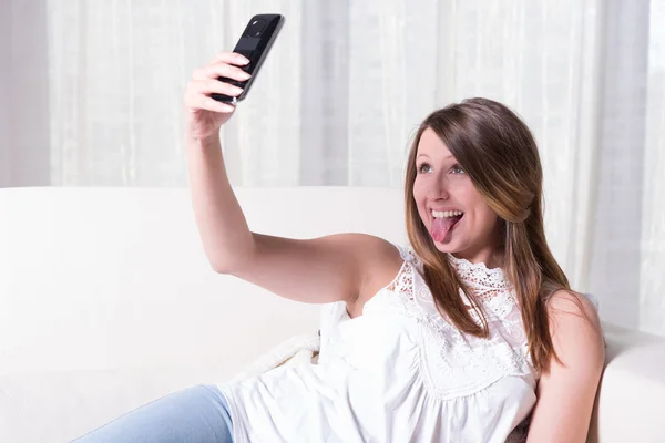 Attractive young girl shooting selfie with tongue out — Stock Photo, Image