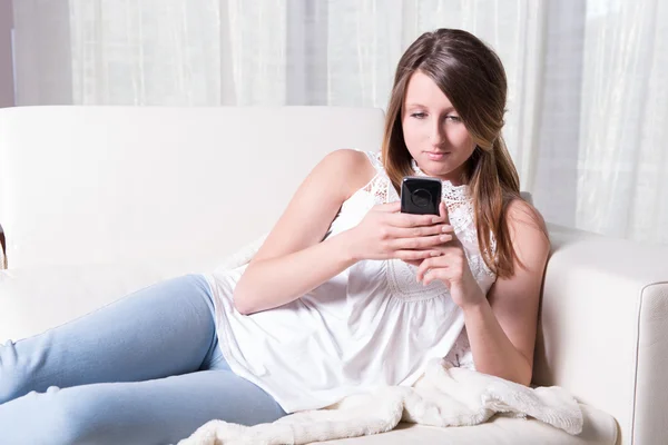 Attractive young girl reading a message on smartphone — Stock Photo, Image