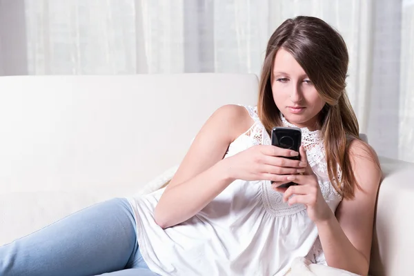 Attractive young girl reading a message on smartphone — Stock Photo, Image