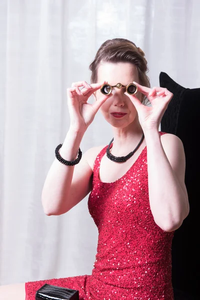 Attractive woman in red dress looking trough magnifying glass — Stock Photo, Image