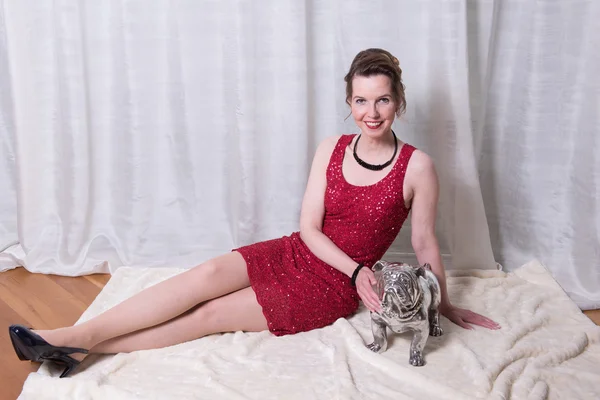 Woman in red dress with dog on blanket — Stock Photo, Image