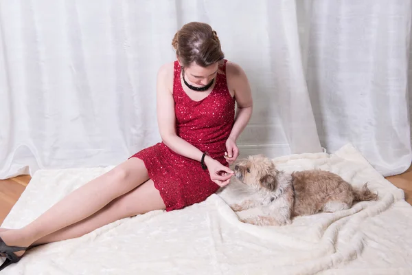 Woman in red dress feeding dog on blanket — Stock Photo, Image