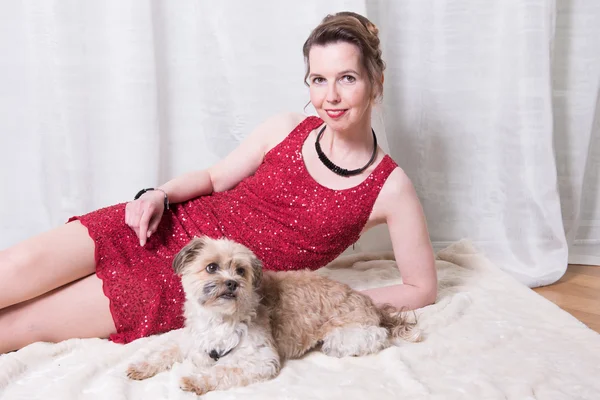 Woman in red dress with dog on blanket — Stock Photo, Image