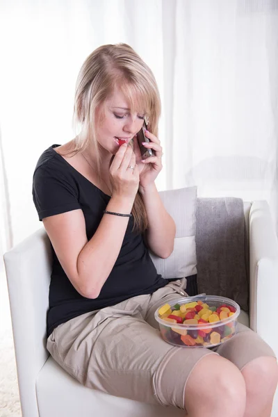 Young woman on the phone eating sweets — Stock Photo, Image